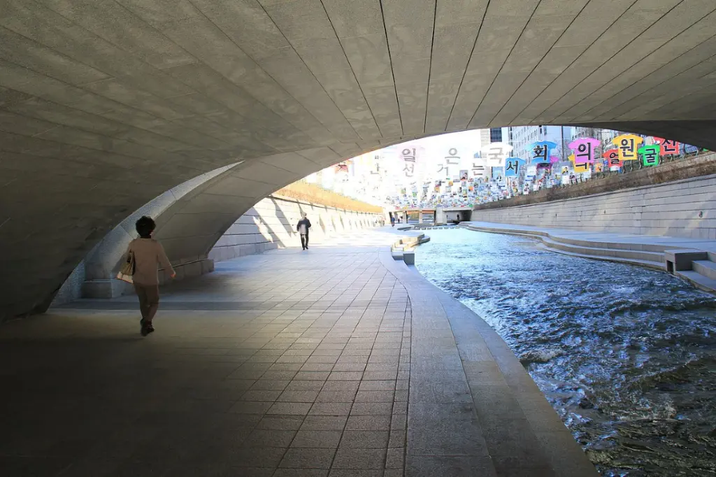 Une dame se balade sous un pont de la rivière cheonggyecheon